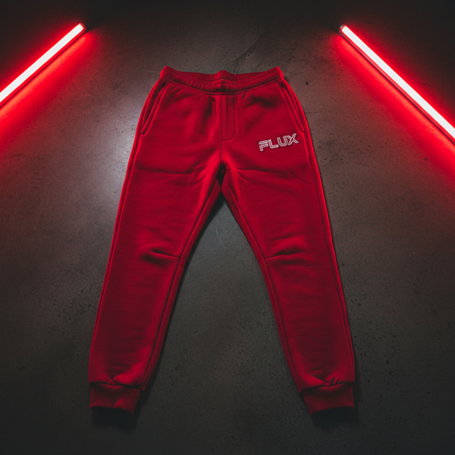 Red FLX AWAY fleece joggers with a white outlined FLUX wordmark at the wearer's left hip.